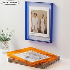 an image of two women in white dresses hanging on the wall above a glass tray