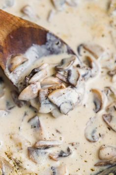 a wooden spoon in a pot filled with mushroom sauce and mushrooms on the stove top