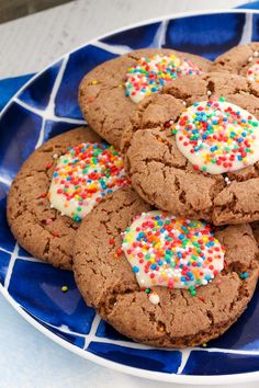 chocolate cookies with white frosting and sprinkles on a blue mosaic plate