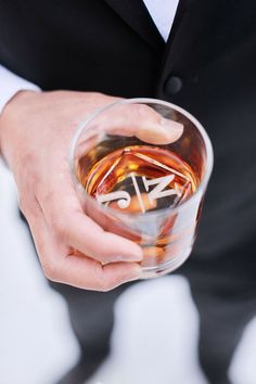 a man in a suit holding a glass filled with alcohol