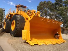 a large yellow dump truck sitting on top of a dirt field