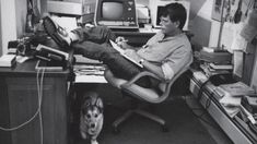 a man sitting in an office chair with his feet on the desk