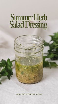 a jar filled with salad dressing sitting on top of a table next to parsley