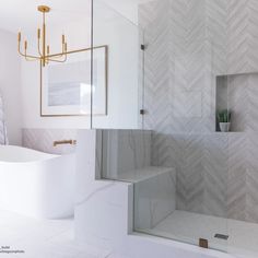 a white bathroom with herringbone tile on the shower wall and tub in the corner