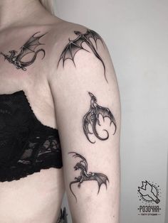 a woman's arm with tattoos on it, including two bats and one demon