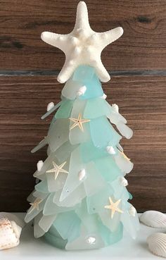 a glass christmas tree with starfishs and seashells