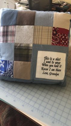 a patchwork pillow with a quote on it sitting on a table next to a sewing machine