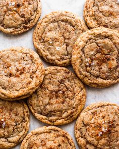 several cookies are arranged on a sheet of wax paper with cinnamon flakes all over them