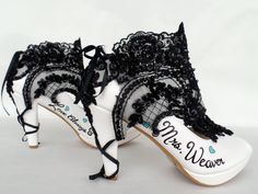 a pair of white and black high heels with lace on the heel, decorated with hearts