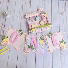 a birthday banner with the word one hanging from it's side on a wooden floor