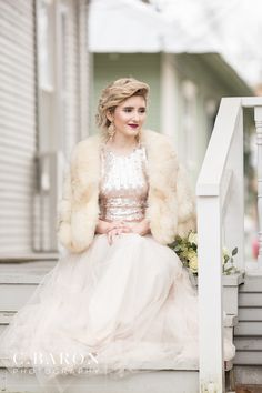 a woman is sitting on the steps wearing a dress and fur coat