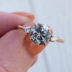 a woman's hand holding an engagement ring with three diamonds on it and the center diamond