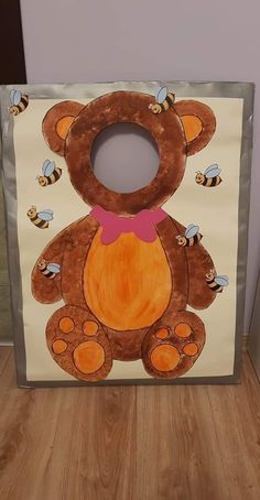 a paper bag with a teddy bear and bees painted on the front, sitting on a wooden floor