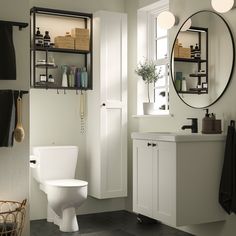 a white toilet sitting under a bathroom mirror next to a sink and a bath tub