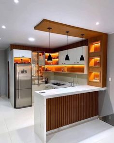 a modern kitchen with an island counter and stainless steel refrigerator freezer in the center