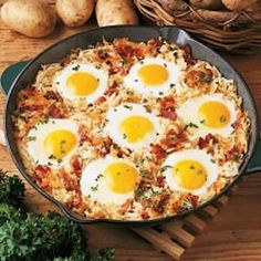 two fried eggs are in a skillet on a wooden table with other food items