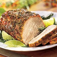 a piece of meat on a plate with lemon wedges and rosemary garnish