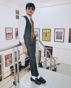 a young man is standing on top of a stair rail wearing a suit and tie