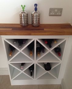 a wine rack with several bottles on top of it and two silver canisters next to it