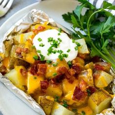 baked potato casserole with sour cream on top and parsley garnish