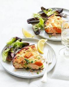 two white plates topped with food next to a glass of water and a fork on a table