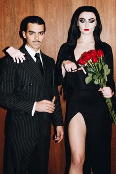 a man and woman dressed up as dracula and the girl is holding a bouquet of roses