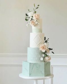 a three tiered cake with flowers on the top and bottom, sitting on a pedestal