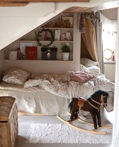 a small child playing with a toy horse in a bedroom next to an unmade bed