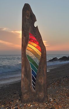 a piece of wood on the beach with a colorful stained glass window in it's center