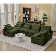 a living room filled with green couches and a white rug on top of a hard wood floor