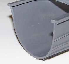 a close up of a gray plastic object on a white surface with no one around it