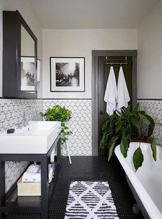 the bathroom is decorated in black and white with greenery on the sink countertop