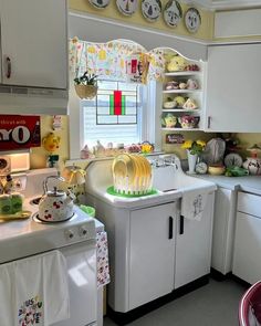 a kitchen filled with lots of white appliances and dishes on top of counter tops next to a window