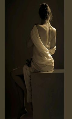 a woman in a white dress sitting on top of a table with her back to the camera