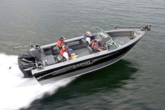 two men and a dog are riding in a motor boat on the water while another man is driving behind them