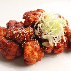 a white plate topped with meat covered in sauce and sprinkled with sesame seeds