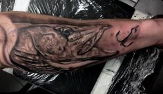 a man with a tattoo on his arm holding a fishing hook and an animal's head