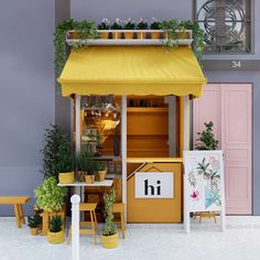 an outdoor cafe with potted plants on the roof and yellow chairs in front of it