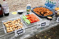 a picnic table with food on it and bottles of water in the backgroud