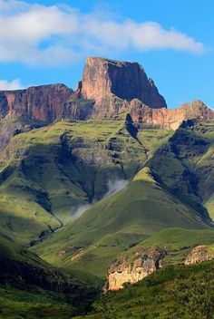 the mountains are covered in green grass and clouds