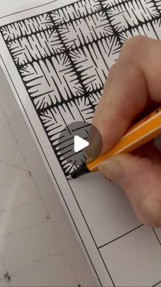 a person holding a pencil in their left hand and drawing on paper with black ink