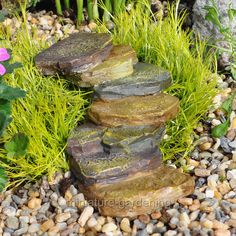 some rocks are stacked on top of each other in the gravel and grass next to flowers