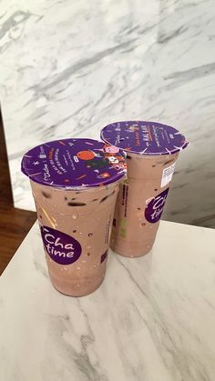 two cups of ice cream sitting on top of a marble counter next to each other