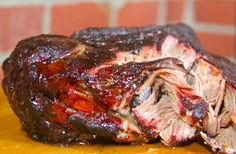 a large piece of meat sitting on top of a cutting board next to a brick wall