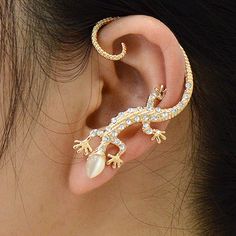 a close up of a person's ear wearing an ear cuff with a lizard on it