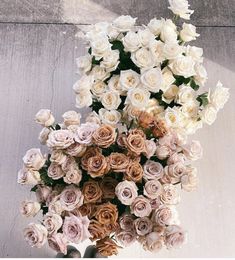 a bunch of white and pink roses in a vase on a table next to a wall