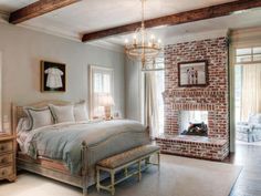 a bedroom with a brick fireplace in the corner and a chandelier hanging from the ceiling