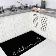 a kitchen area with white cabinets and black floor mats that read, i love you