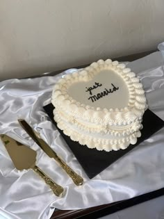 a heart shaped cake sitting on top of a table next to utensils and a knife