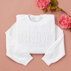 the bride sweatshirt is next to pink flowers